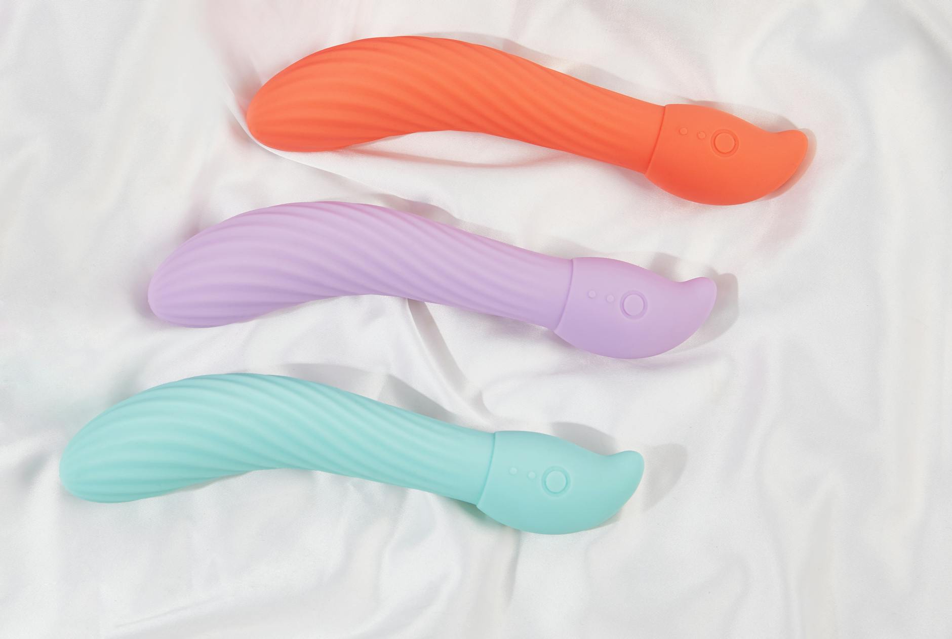Una mano sostiene un vibrador azul sobre un recipiente decorativo de vidrio, simbolizando la exploración suave de la intimidad