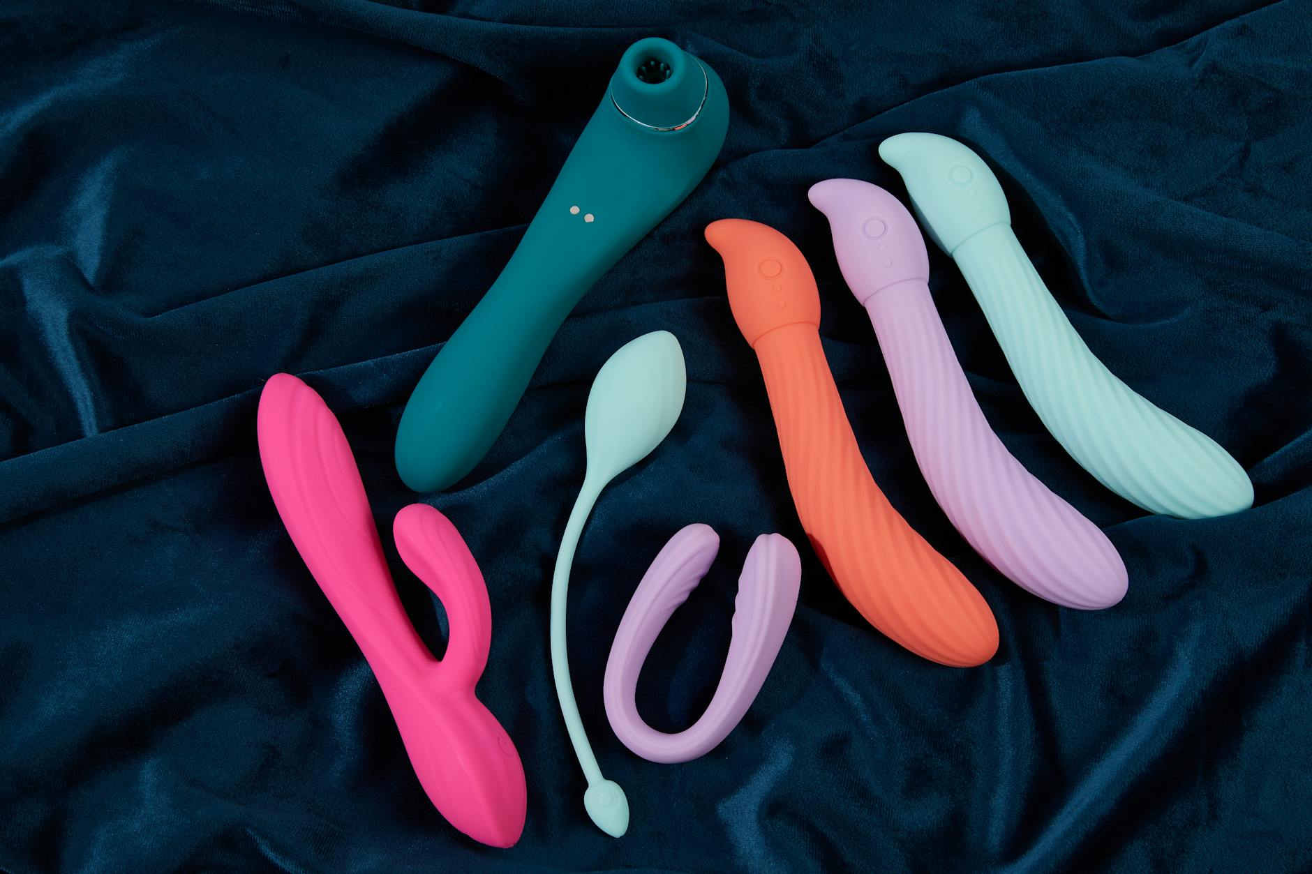 Mano sosteniendo un vibrador naranja contra un fondo púrpura minimalista