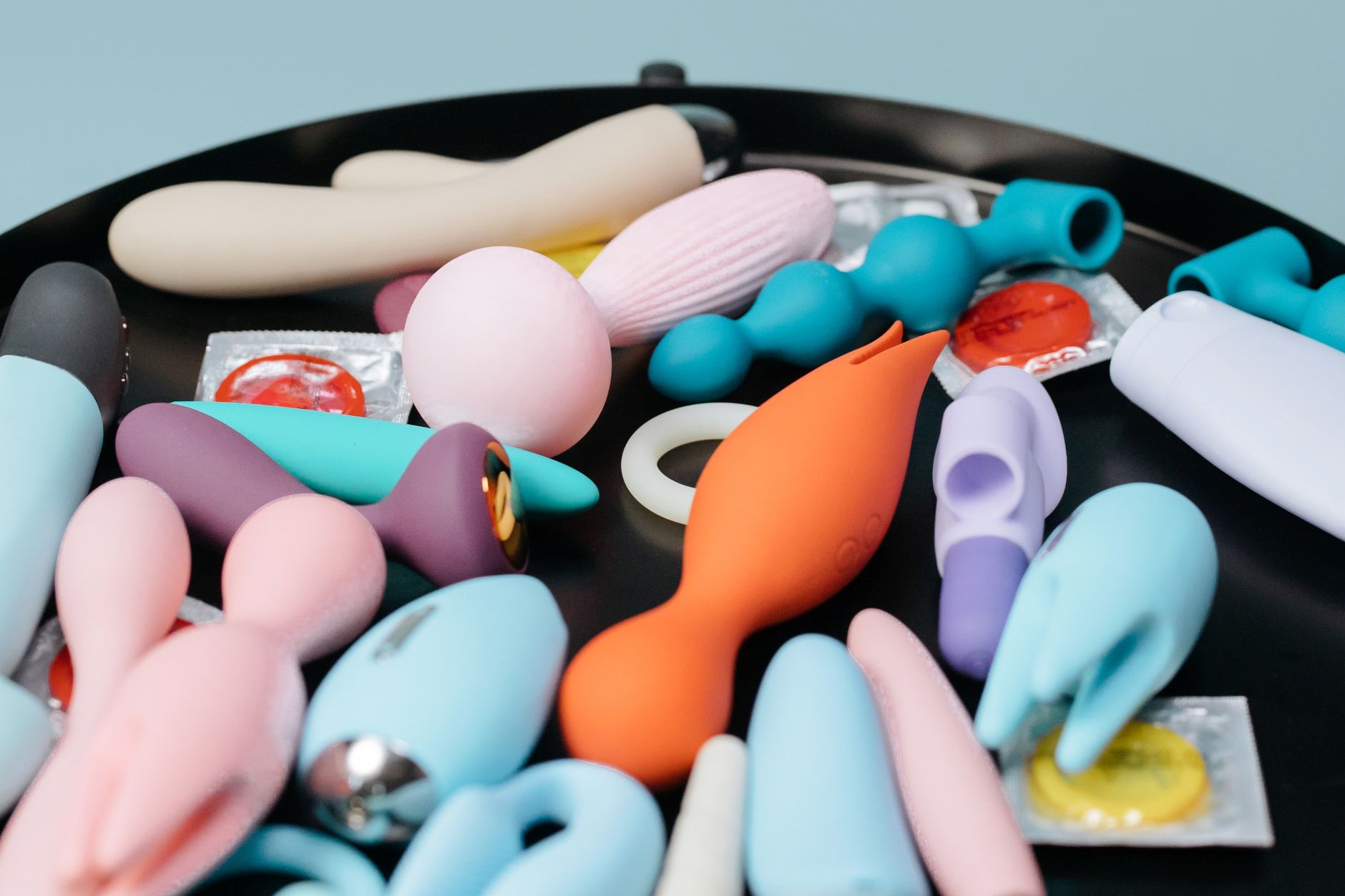 Manos sosteniendo un vibrador de masaje personal azul contra un suéter tejido