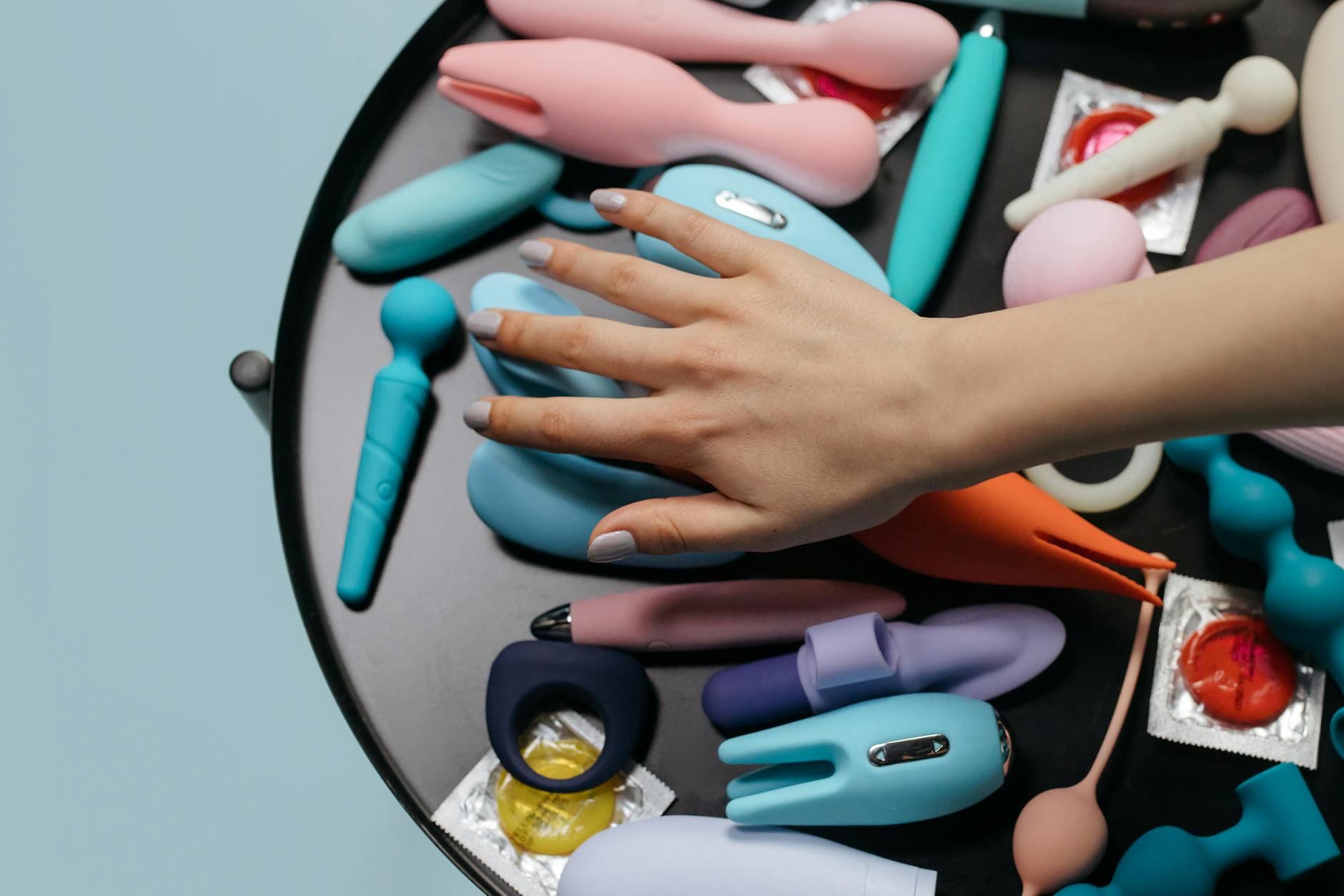 Una mano sosteniendo un vibrador naranja contra un fondo minimalista púrpura, mostrando sensualidad moderna