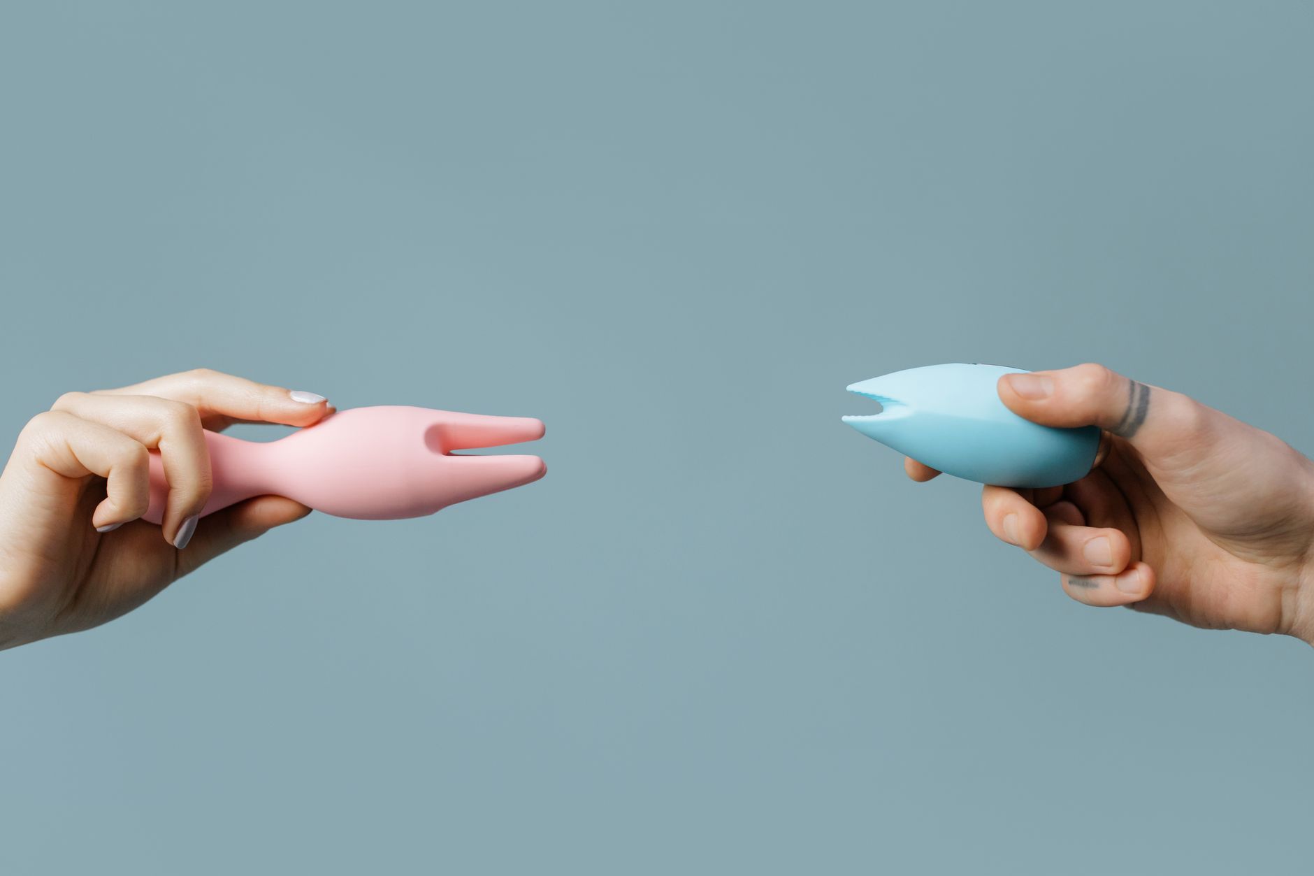 Manos sosteniendo un vibrador azul con elegancia contra un fondo texturizado.