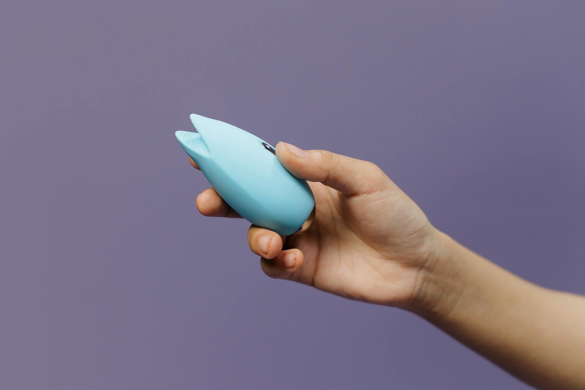 Pareja joven sosteniendo un vibrador azul juntos, simbolizando la intimidad moderna y la reconexión