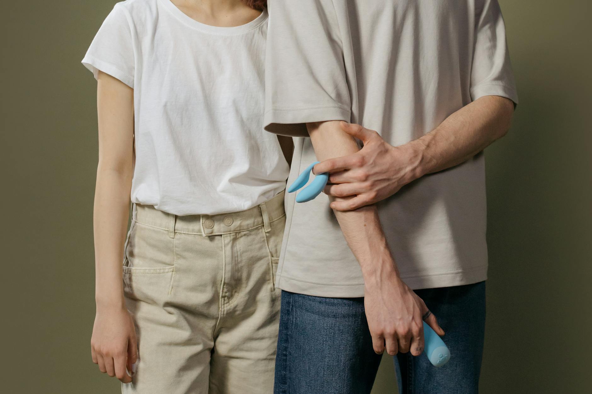 Pareja joven parada juntos en la intimidad, explorando vibradores modernos